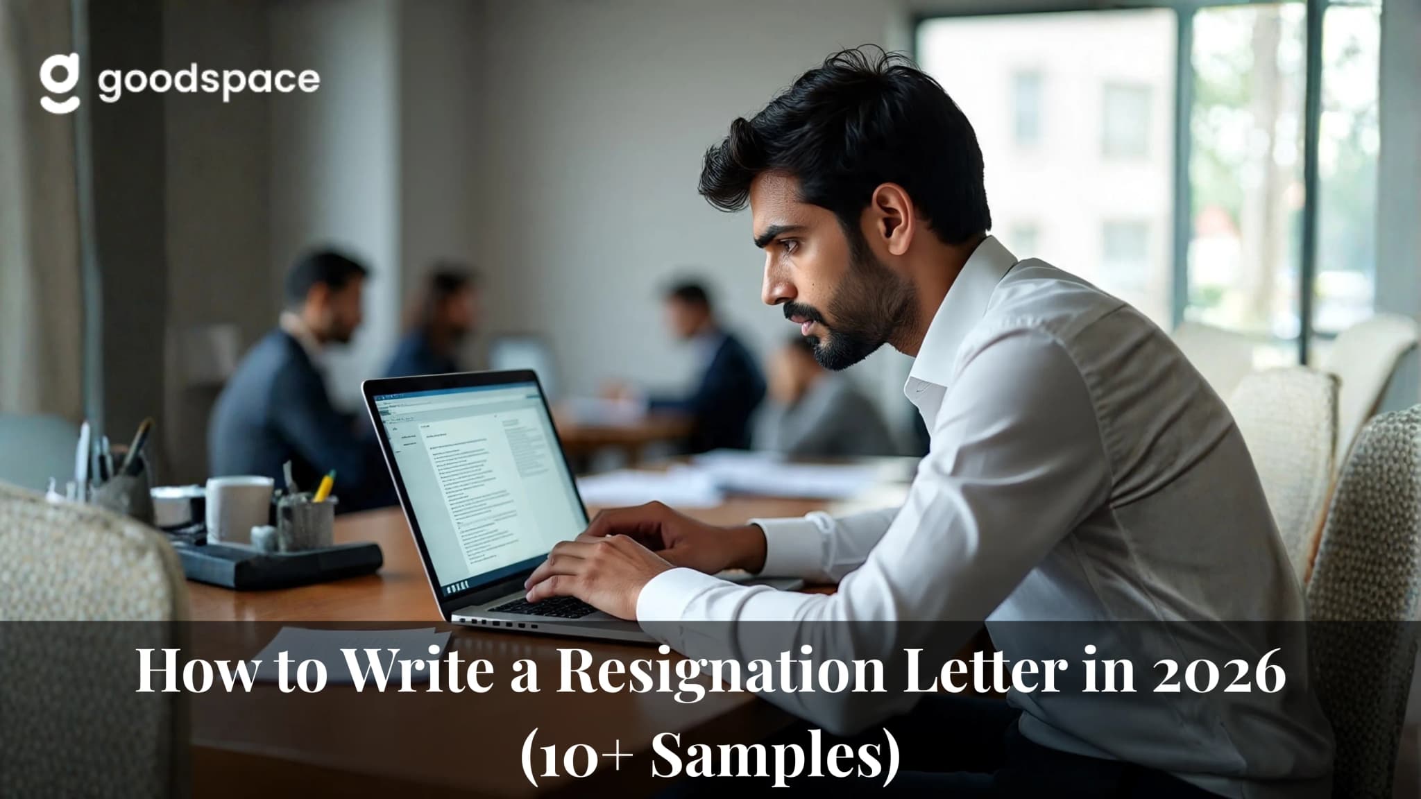 Man in a white shirt typing a resignation letter on a laptop while colleagues meet behind him