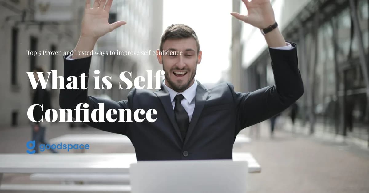 Man in a suit raising both arms in triumph behind a laptop, overlaid with What is Self Confidence